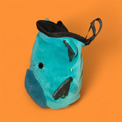 Teal coverted plush toy into handmade chalk bag with black glittery wings on an orange background side view